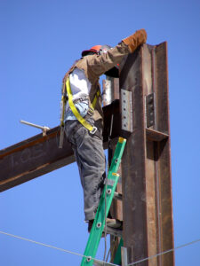 Construction worker climbing to the top of a steel beam high rise building project